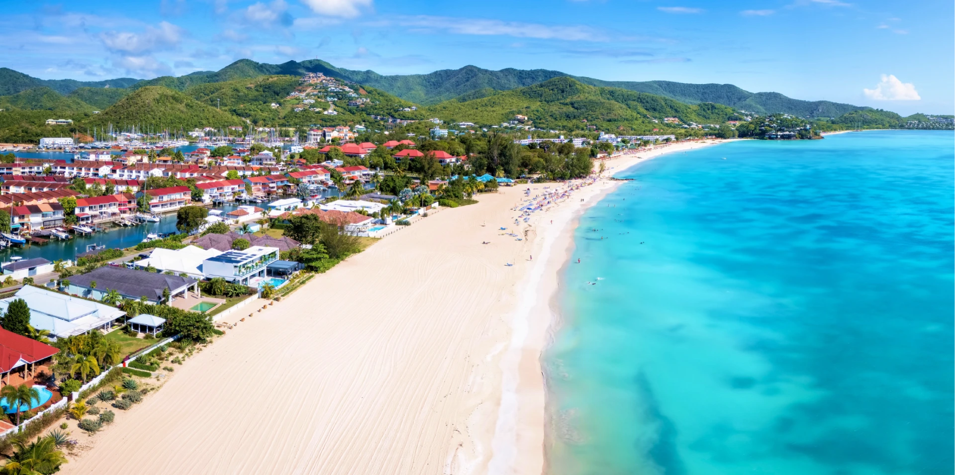 Aerial view of a long white-sand beach beside a waterfront community