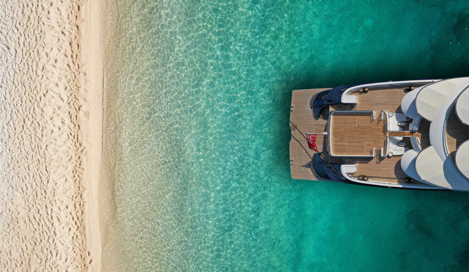 Aerial view of a yacht moored beside a white-sand beach