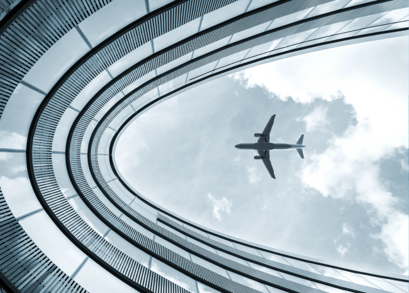 Airplane flying overhead, seen through a curved glass roof