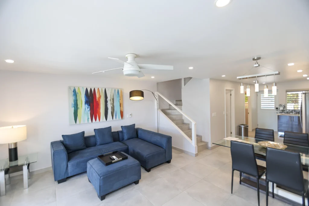 Two Bedroom Superior villa living room with blue sofa, dining area and staircase